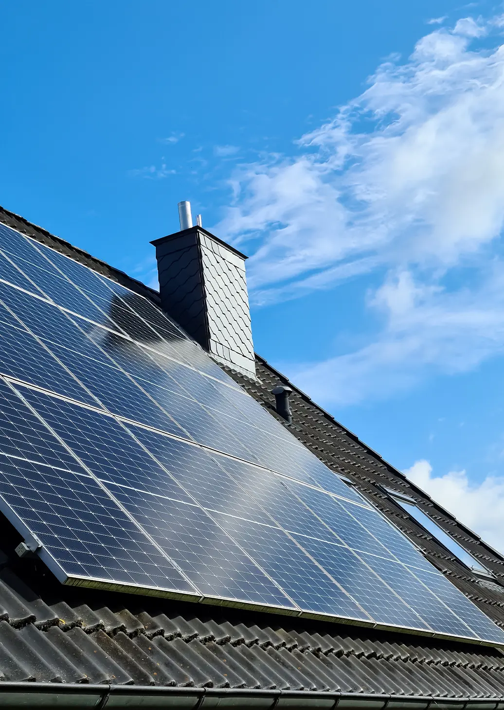 Panneaux solaires photovoltaïques installés sur toiture ardoisée en Wallonie sous ciel bleu
