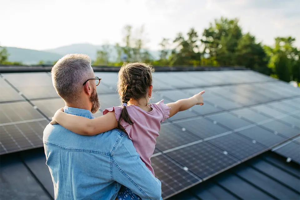 Père et enfant devant les panneaux solaires installés sur leur maison en Wallonie — Solution Énergie