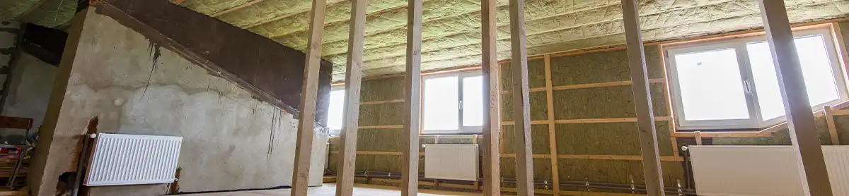 Comble aménageable en cours d'isolation par l'intérieur — laine de roche entre chevrons et charpente bois apparente en Belgique
