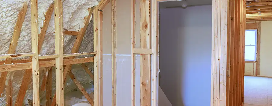 Charpente en bois apparente avec isolation par mousse polyuréthane projetée blanche sur la sous-toiture, dans des combles aménageables en cours de finition en Belgique