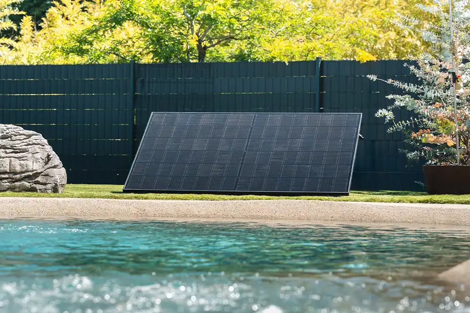 Station solaire Kodak® Plug & Play 450 W posée au sol dans un jardin résidentiel en Belgique, près d'une piscine
